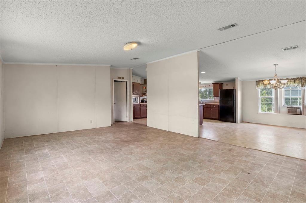 An open-concept living area with tile flooring leads into a kitchen with dark wood cabinets — 13317 MOON ROAD, BROOKSVILLE, FL