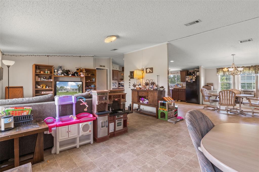 A living room and dining area feature light-colored walls, tile flooring, and children's play sets — 13317 MOON ROAD, BROOKSVILLE, FL