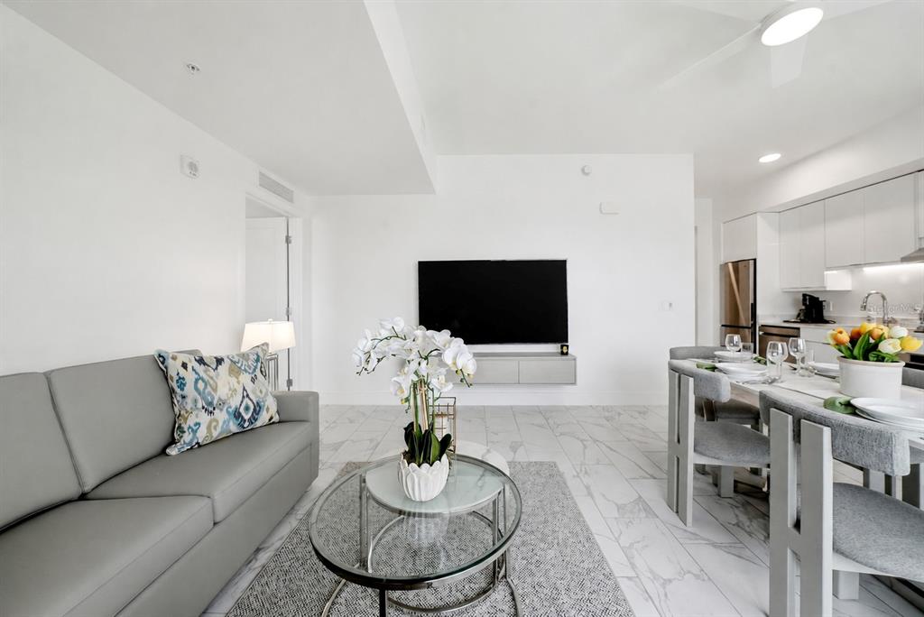 A modern living and dining area with white walls, marble floors, and gray furniture — 411 E SHORE DRIVE UNIT 713, CLEARWATER BEACH, FL