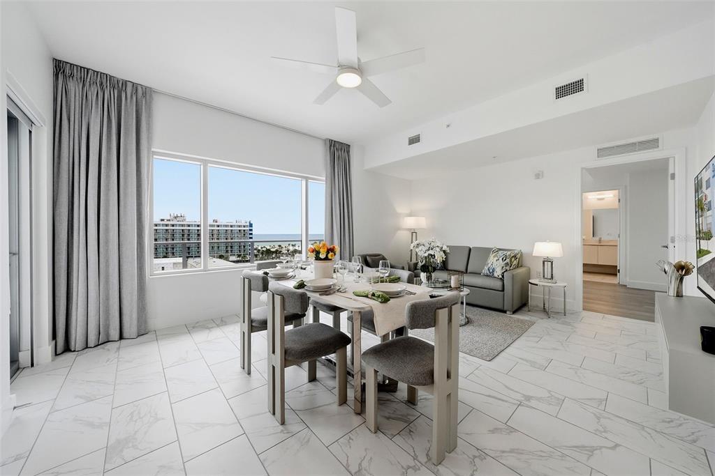 A dining area and living room with white tile floors, a ceiling fan, and ocean views — 411 E SHORE DRIVE UNIT 713, CLEARWATER BEACH, FL