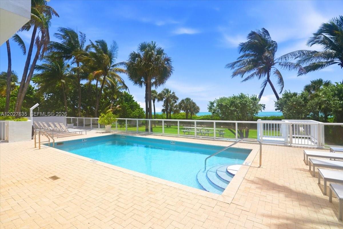 A rectangular swimming pool is surrounded by a paved deck, palm trees, and ocean views — 8911 Collins Ave # 601, Surfside FL 33154, SURFSIDE, FL
