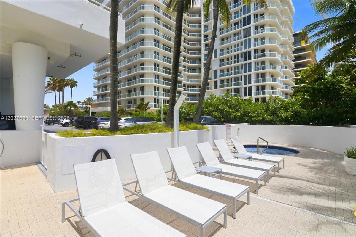 A row of white lounge chairs sits on a paved patio beside a small pool — 8911 Collins Ave # 601, Surfside FL 33154, SURFSIDE, FL