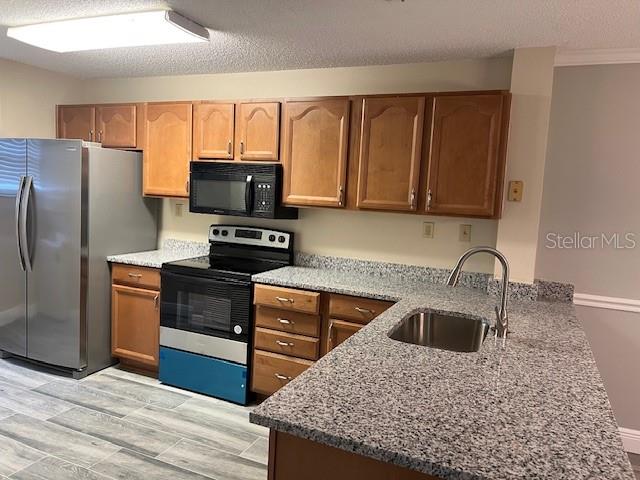 A kitchen features wood cabinets, granite countertops, stainless steel appliances, and a gray tile floor — 14810 PAR CLUB CIRCLE, TAMPA, FL