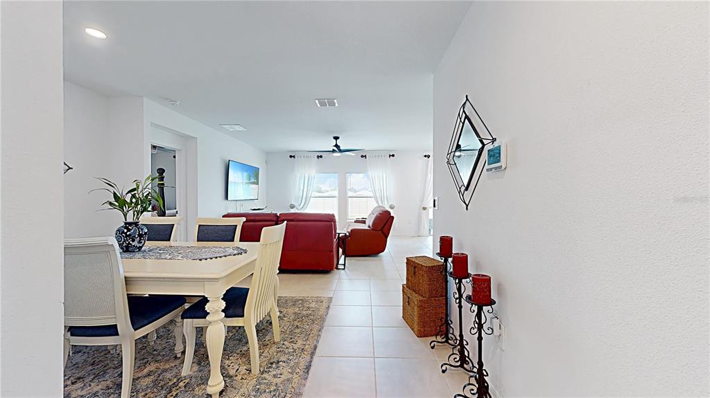 A dining area with a white table leads into a living room with red furniture — 33941 SKY BLOSSOM CIRCLE, LEESBURG, FL