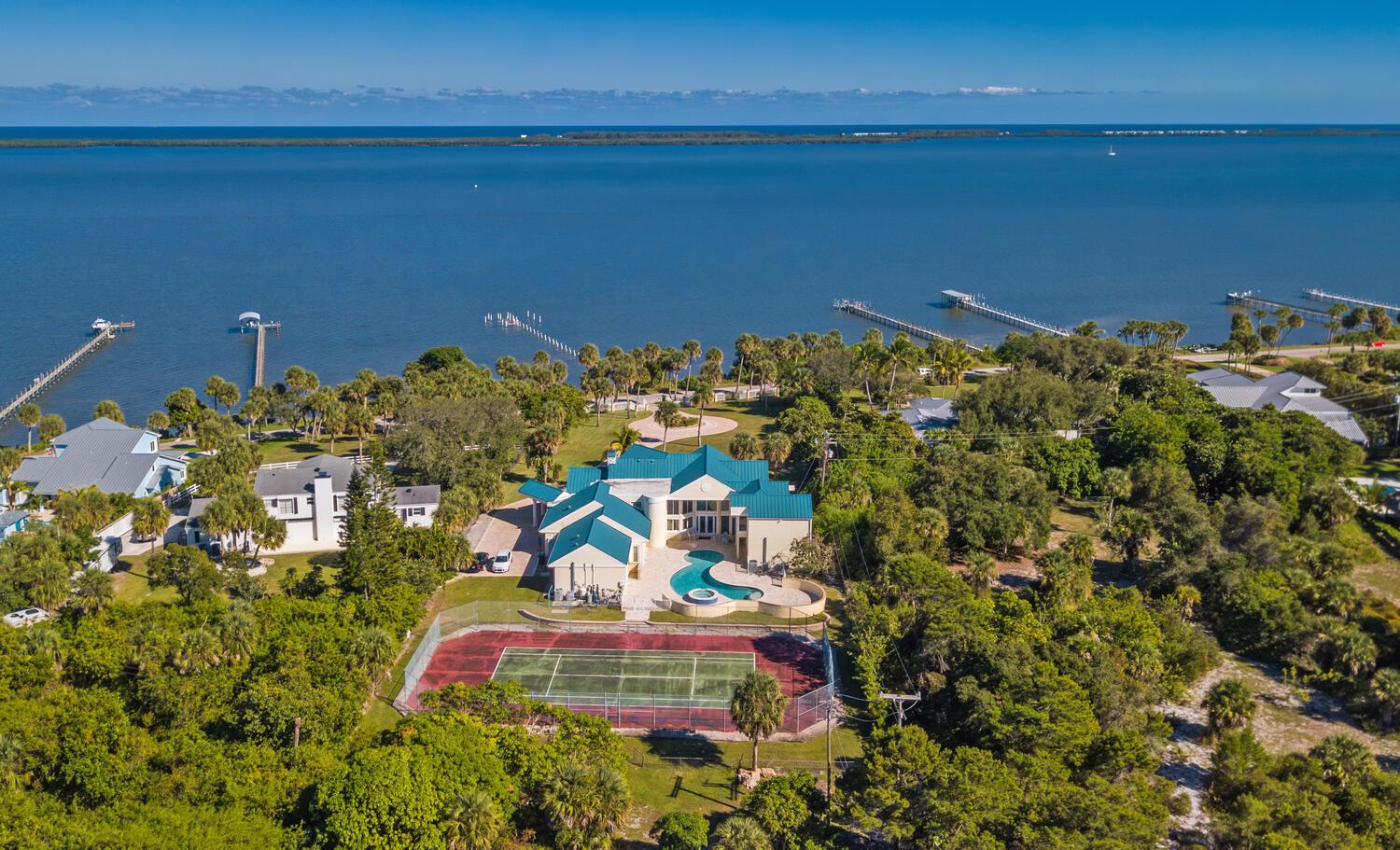 An aerial view of a waterfront estate featuring a tennis court, pool, and multiple buildings — 3343 S Indian River Drive, Fort Pierce FL 34982, FORT PIERCE, FL