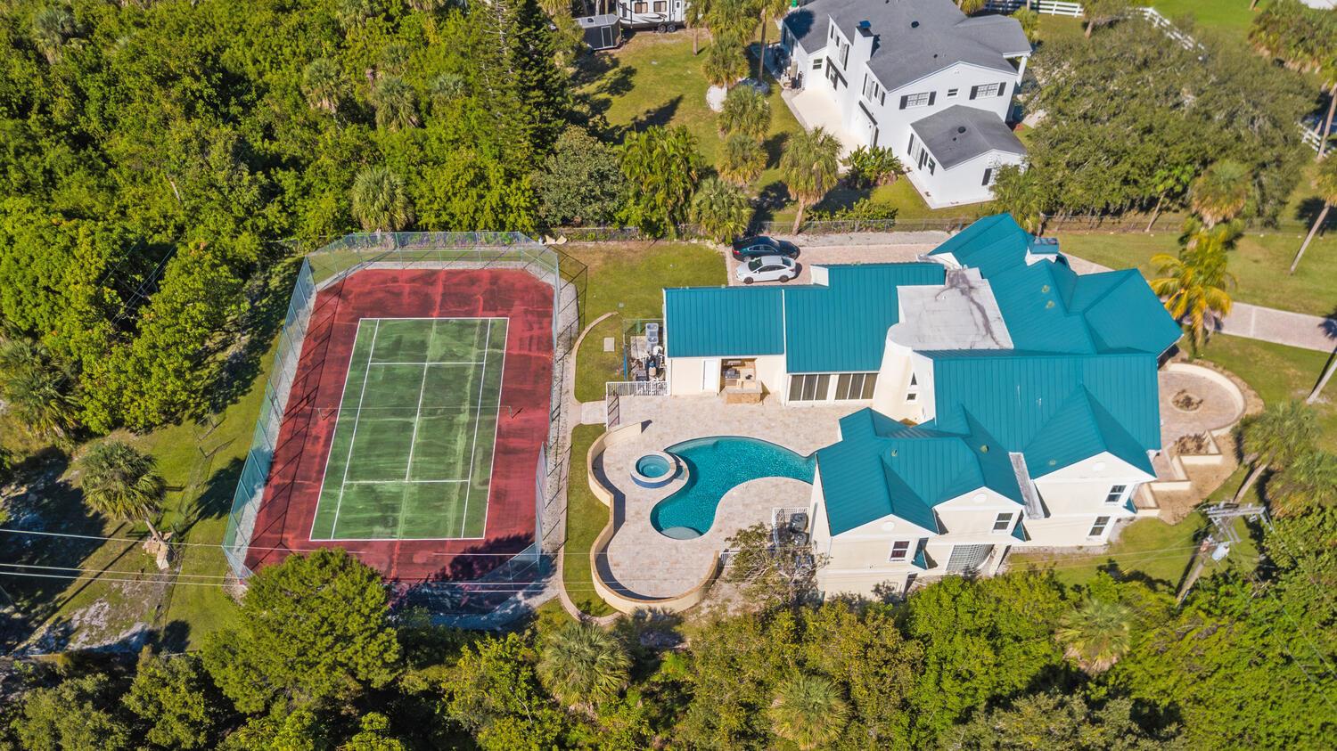An aerial view shows a house with a teal roof, a swimming pool, and a tennis court — 3343 S Indian River Drive, Fort Pierce FL 34982, FORT PIERCE, FL