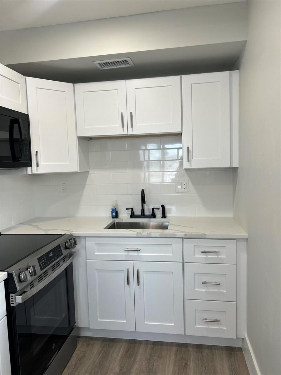 A kitchen features white shaker cabinets, a stainless steel sink, and a subway tile backsplash — 1980 Sunset Avenue # 12, FL 33461, FL