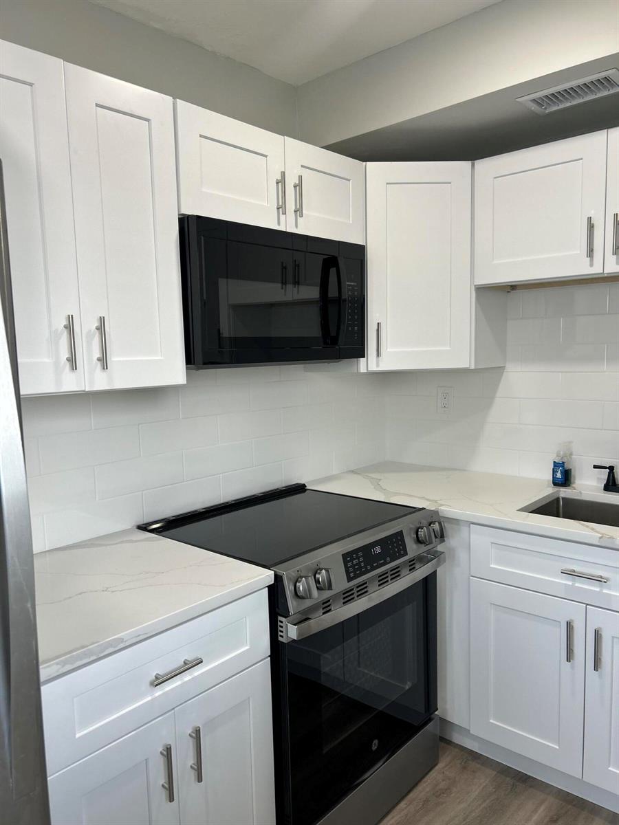 A kitchen features white shaker cabinets, a black microwave, a stainless steel stove, and countertops — 1980 Sunset Avenue # 12, FL 33461, FL
