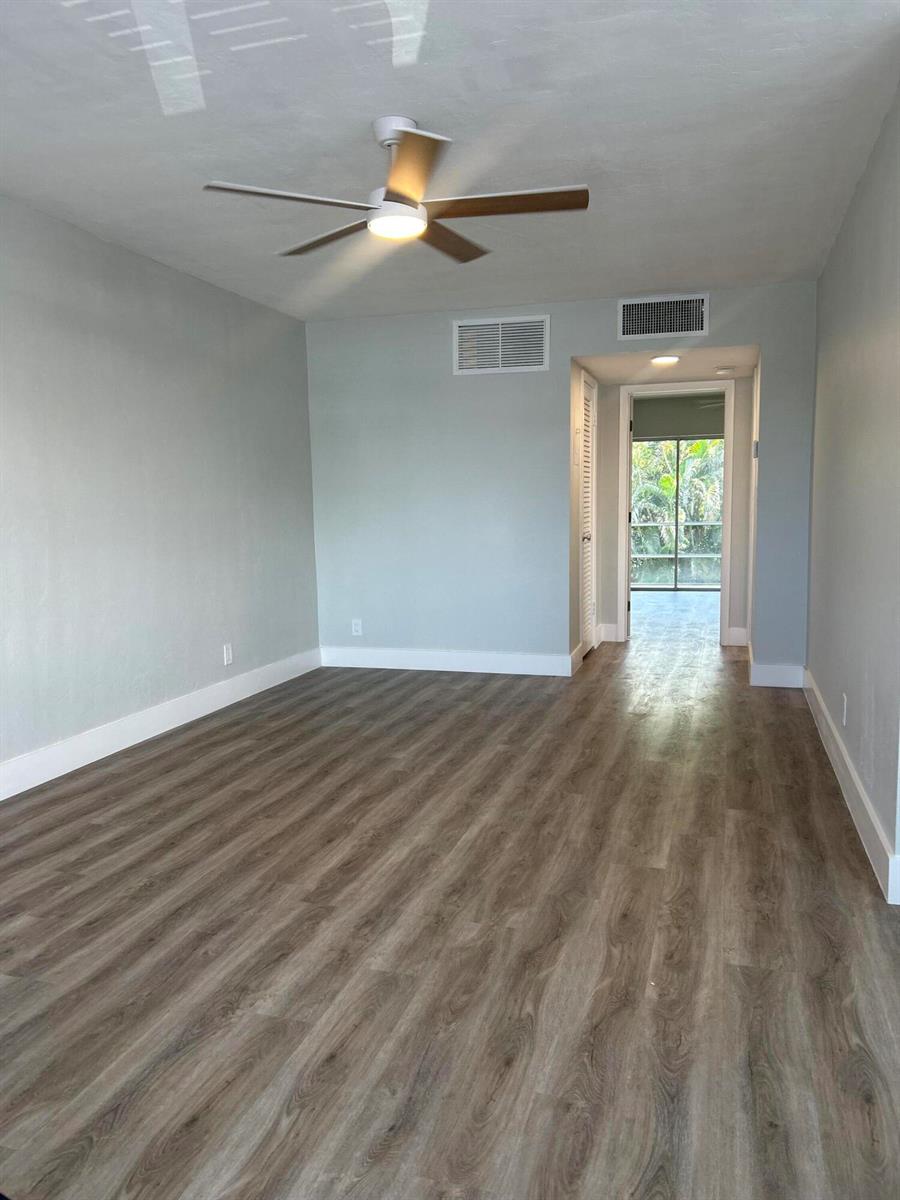 An empty room with light gray walls, wood-look flooring, a ceiling fan, and a doorway — 1980 Sunset Avenue # 12, FL 33461, FL