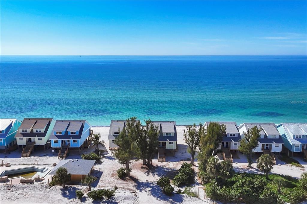 An aerial view shows a row of beach houses situated directly along the oceanfront — 301 S GULF BOULEVARD UNIT 10, PLACIDA, FL