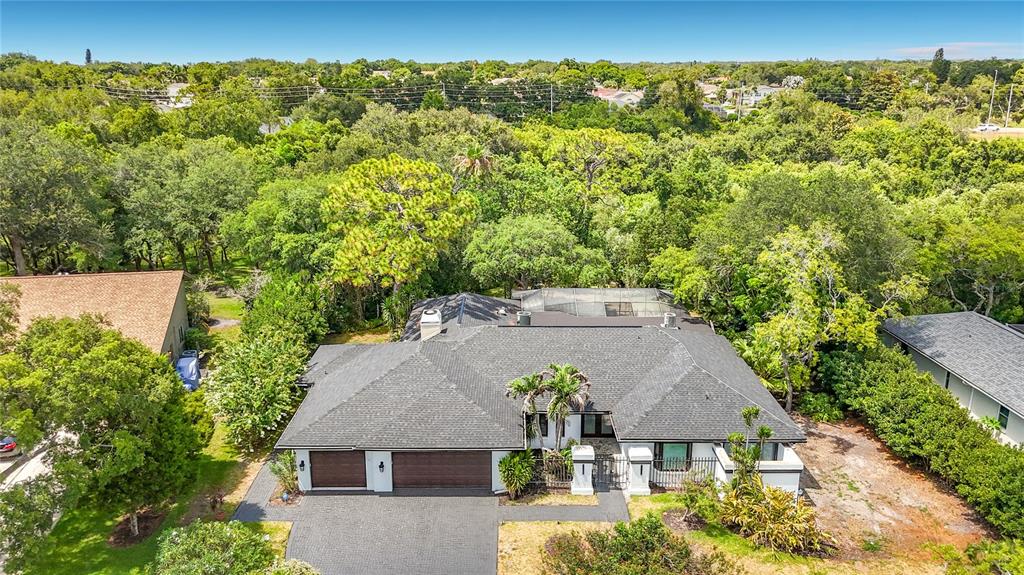 An aerial view shows a single-story house with a dark roof and a paved driveway — 1494 STURBRIDGE COURT, DUNEDIN, FL