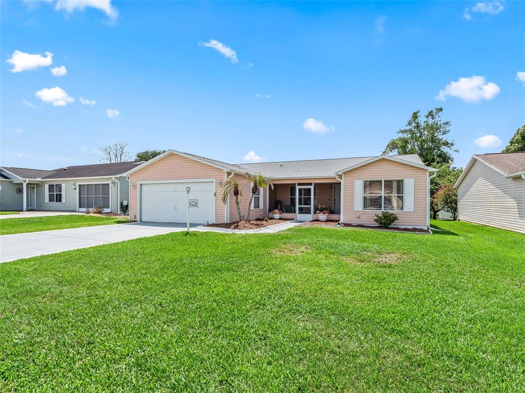 A single-story peach-colored house with a two-car garage and a front lawn — 1304 GUADALUPE COURT, THE VILLAGES, FL