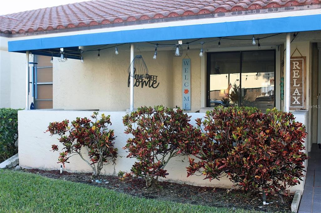 An exterior view of a house at dusk featuring a blue awning and string lights — 8804 40TH LANE N, PINELLAS PARK, FL