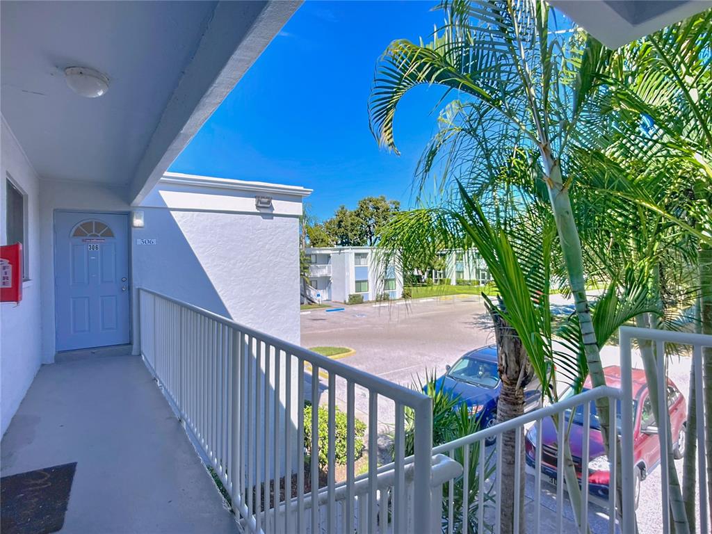An exterior view from a balcony overlooking a parking lot with palm trees and buildings — 5310 26TH STREET W UNIT 306, BRADENTON, FL