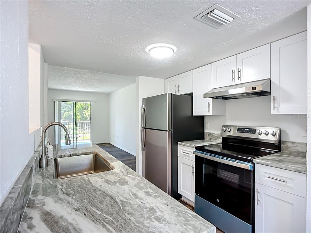 A kitchen features white cabinets, stainless steel appliances, and gray marble-patterned countertops — 5310 26TH STREET W UNIT 306, BRADENTON, FL