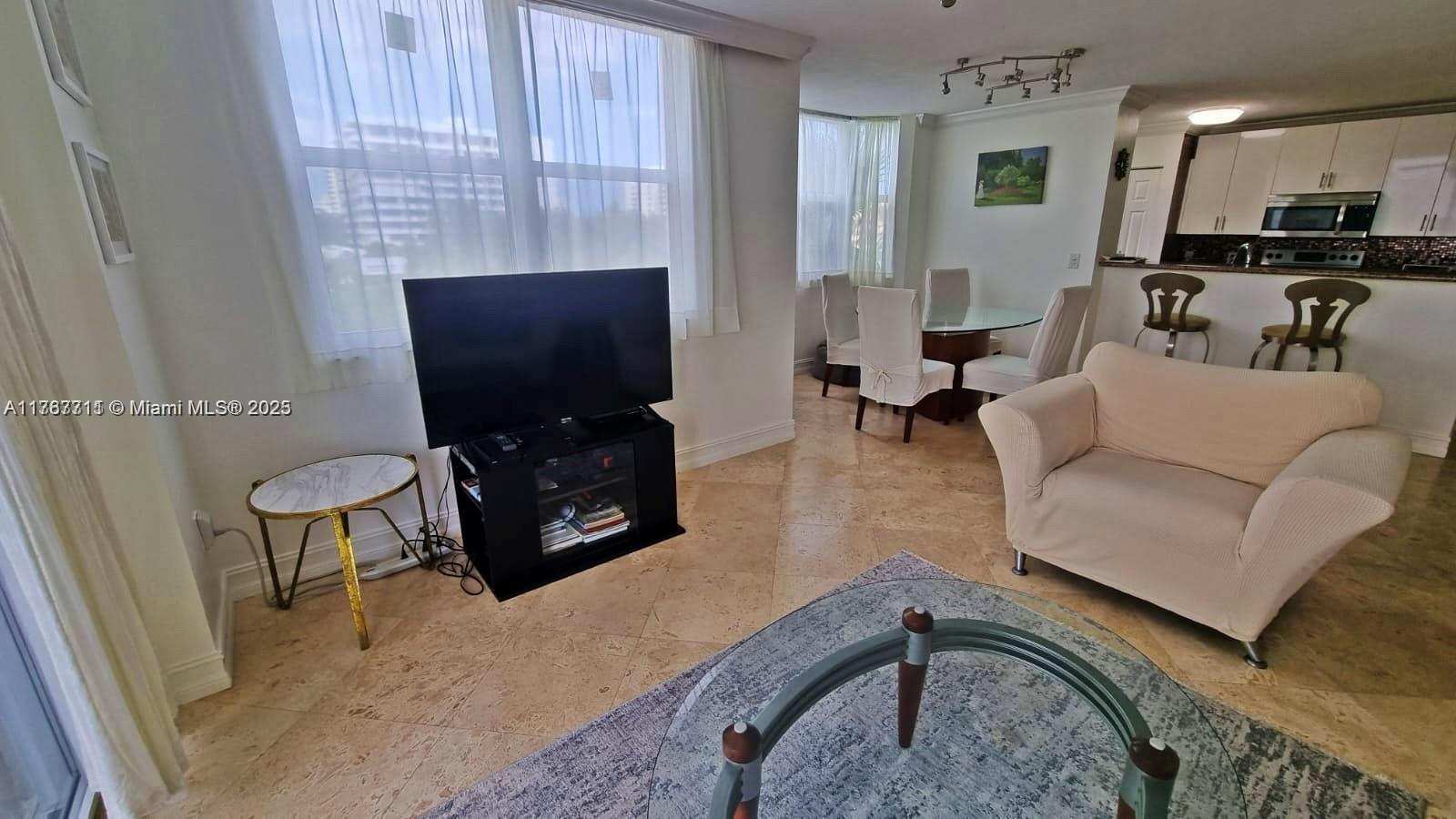 A living room with tile floors, a television, and an open kitchen in the background — 3594 S Ocean Blvd # 402, Highland Beach FL 33487, HIGHLAND BEACH, FL