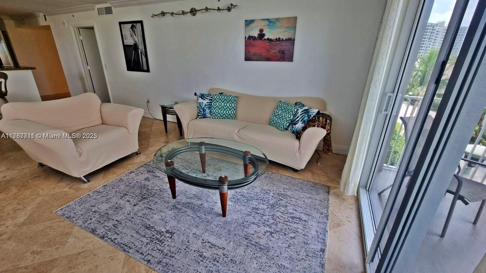 A living room features a beige sofa and armchair, a glass coffee table, and tile flooring — 3594 S Ocean Blvd # 402, Highland Beach FL 33487, HIGHLAND BEACH, FL