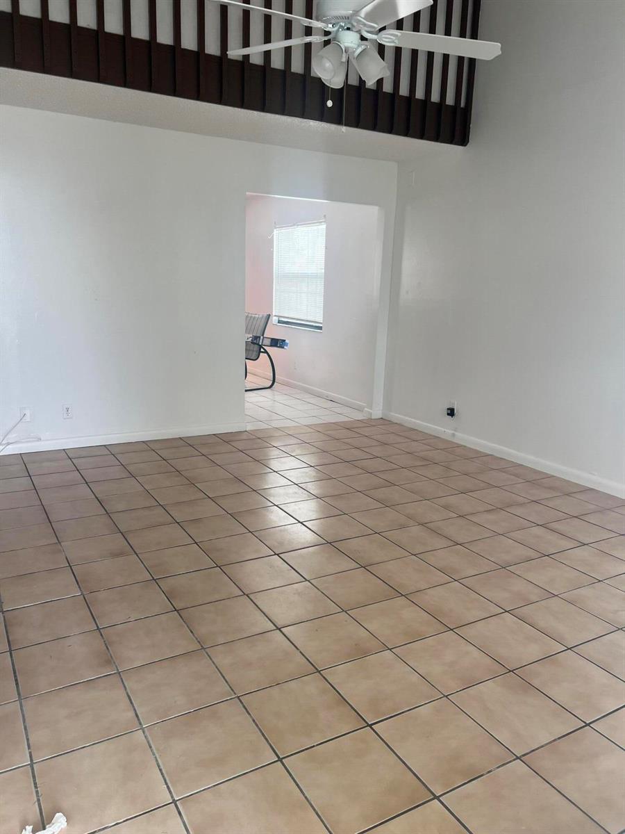 An empty room with tan tile flooring, white walls, and a ceiling fan — 57 Peachtree Place, Boynton Beach FL 33436, BOYNTON BEACH, FL