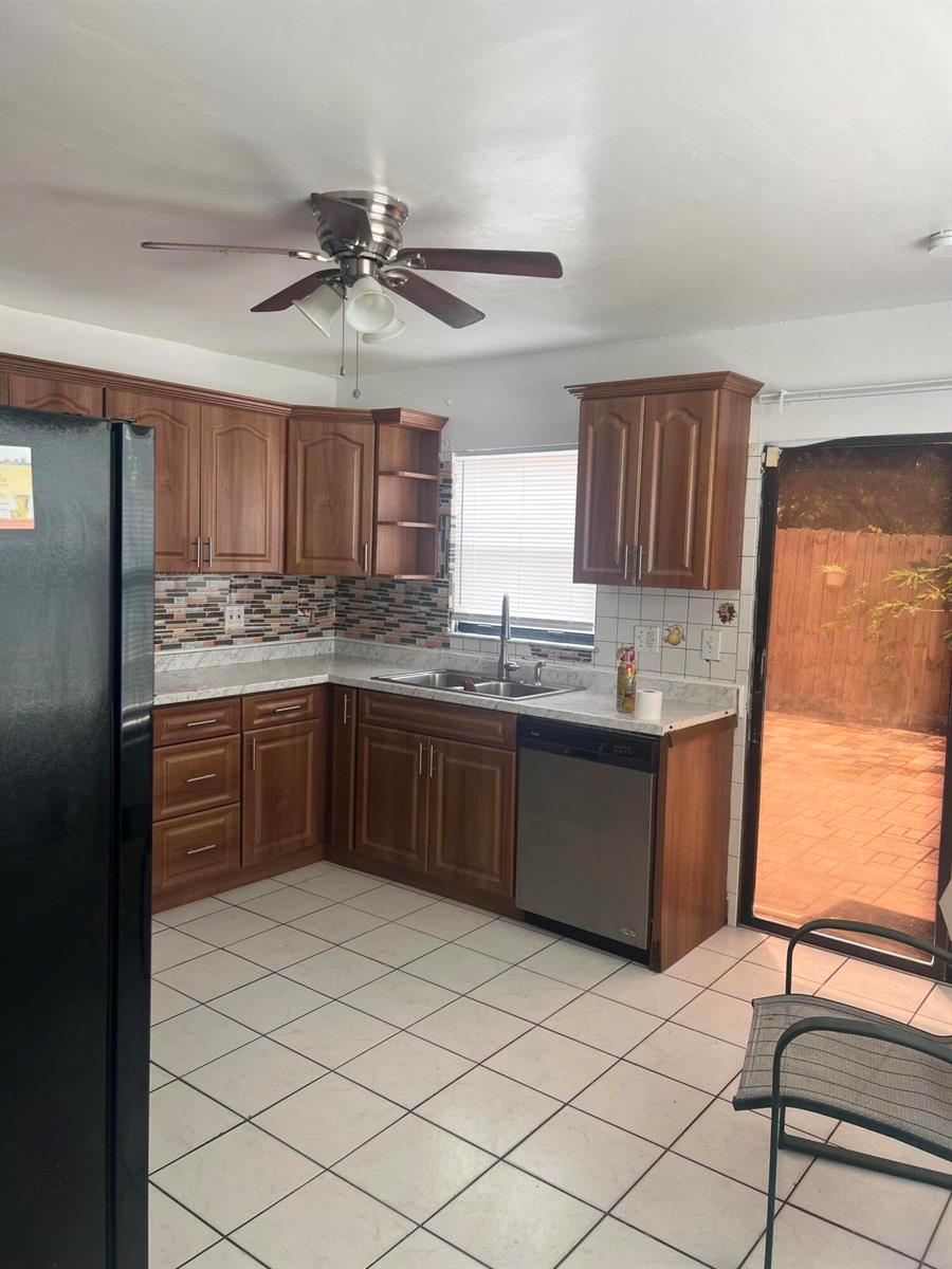 A kitchen with wood cabinets, tiled floors, a ceiling fan, and a sliding glass door — 57 Peachtree Place, Boynton Beach FL 33436, BOYNTON BEACH, FL
