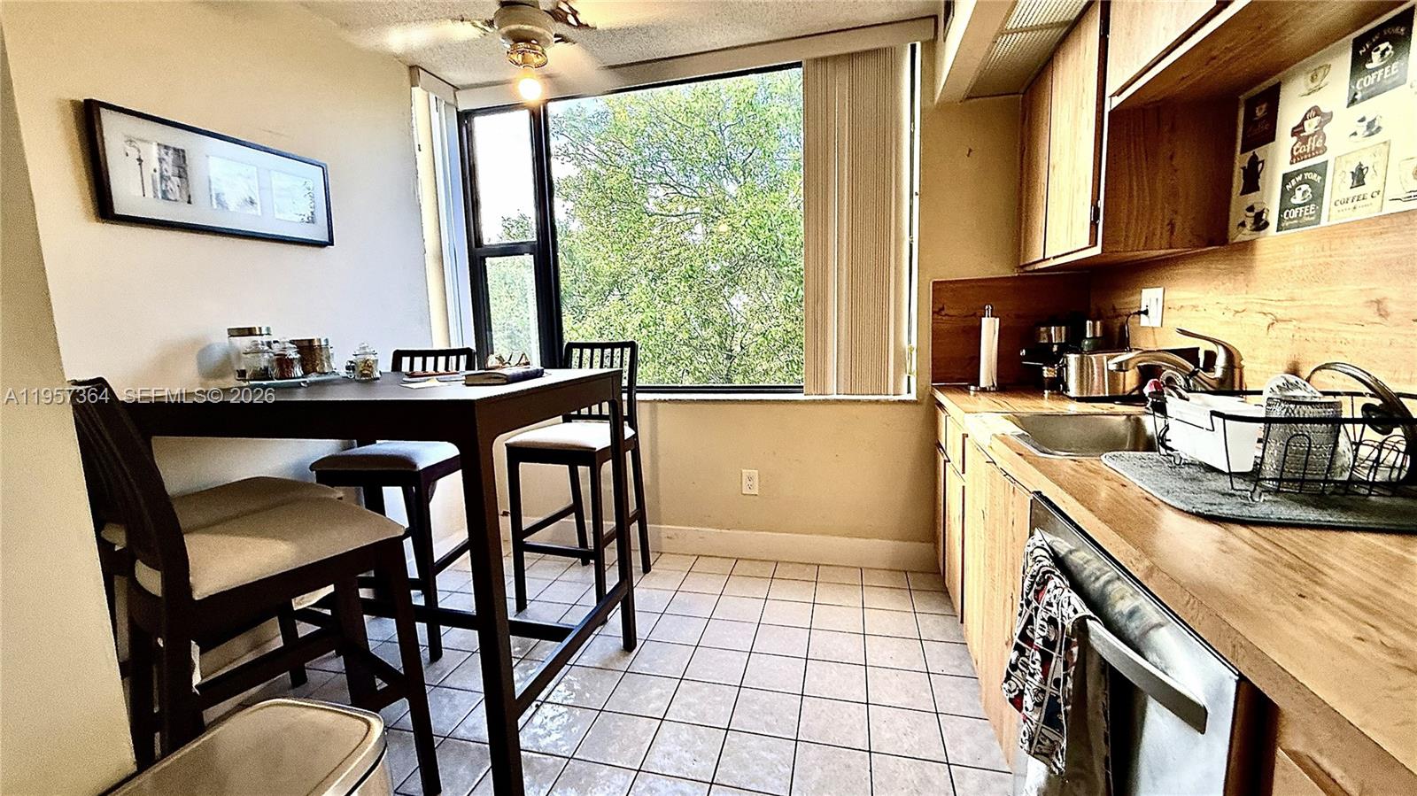 A kitchen with wooden cabinets, a tiled floor, and a dining table by a window — 6800 Cypress Rd # 501, Plantation FL 33317, PLANTATION, FL