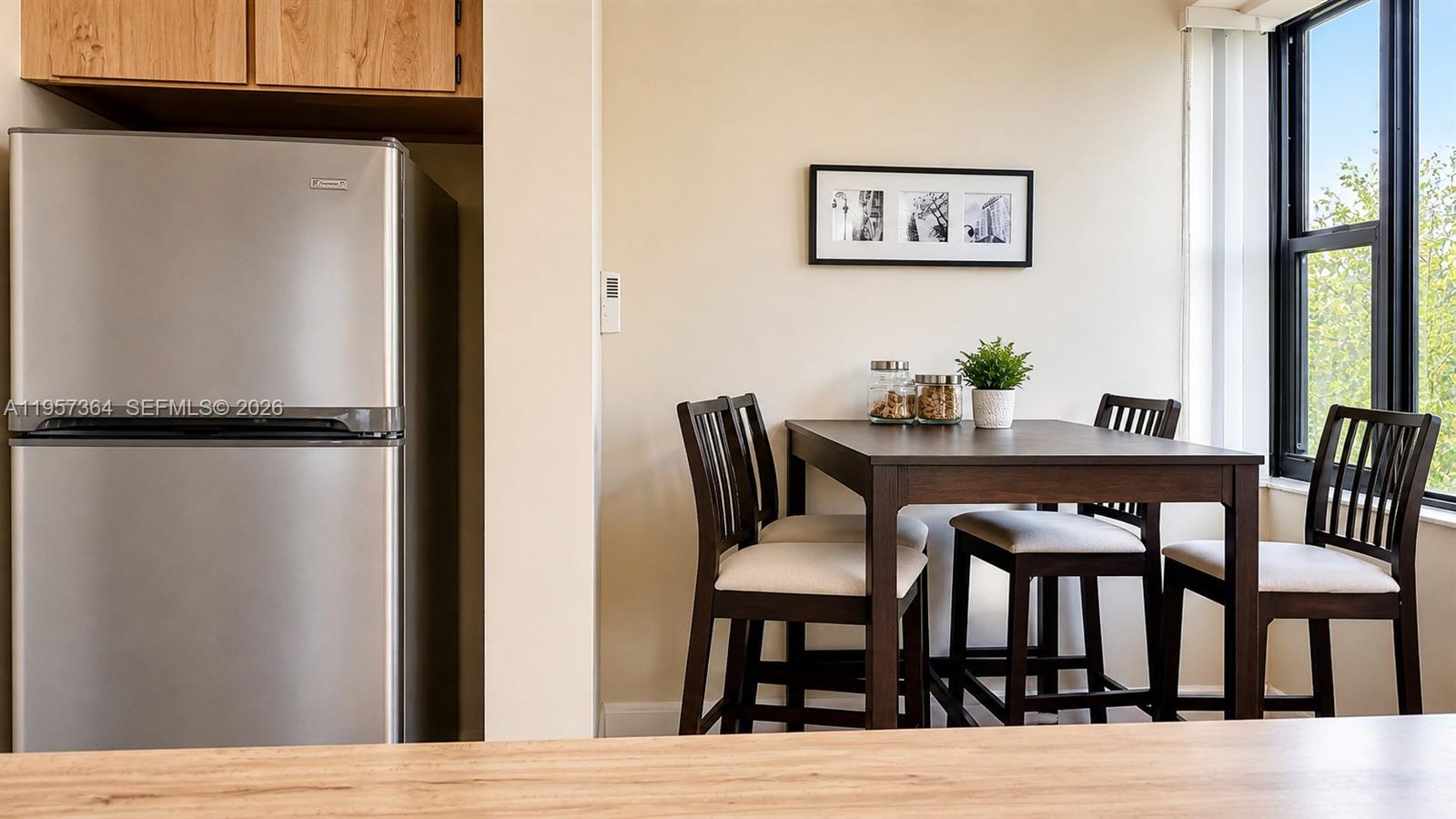 A dining area features a dark wood table with four chairs next to a stainless refrigerator — 6800 Cypress Rd # 501, Plantation FL 33317, PLANTATION, FL
