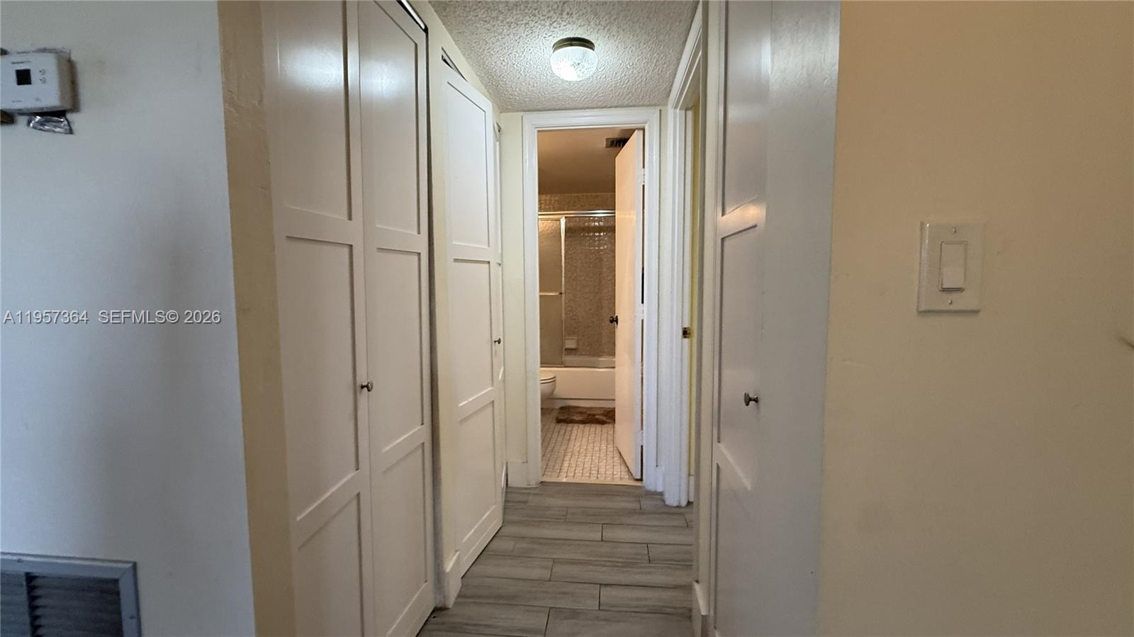 A hallway with white closet doors leads to a bathroom with a tiled shower — 6800 Cypress Rd # 501, Plantation FL 33317, PLANTATION, FL