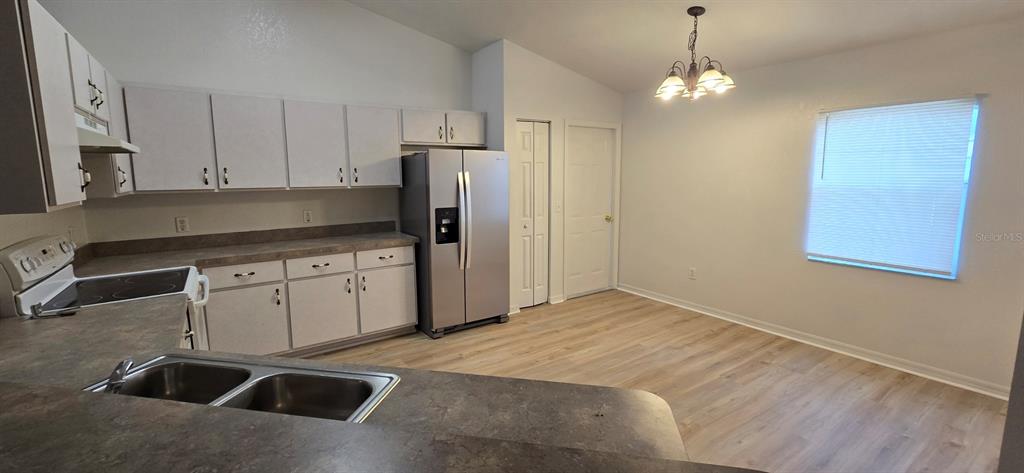A kitchen with white cabinets, stainless steel appliances, and light wood-look flooring — 6875 SE 52ND STREET, OCALA, FL