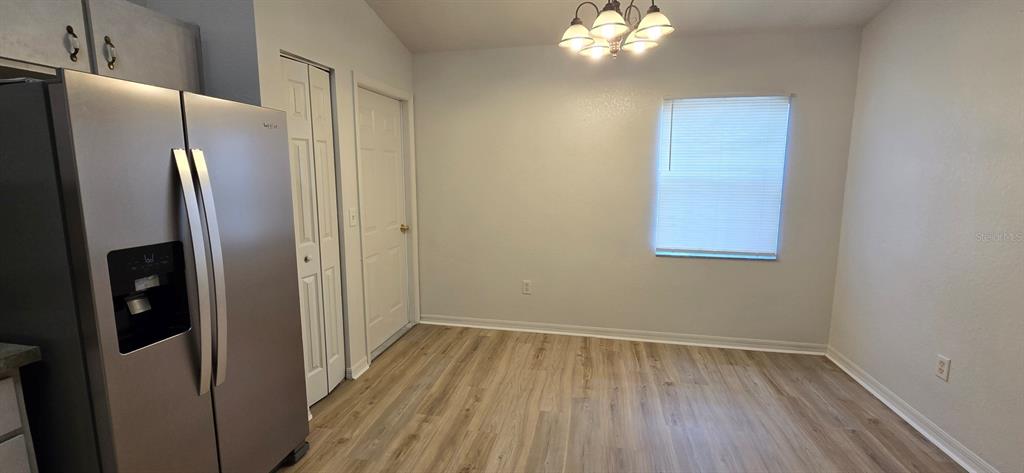 A dining area features light wood-look flooring, a stainless steel refrigerator, and a window — 6875 SE 52ND STREET, OCALA, FL