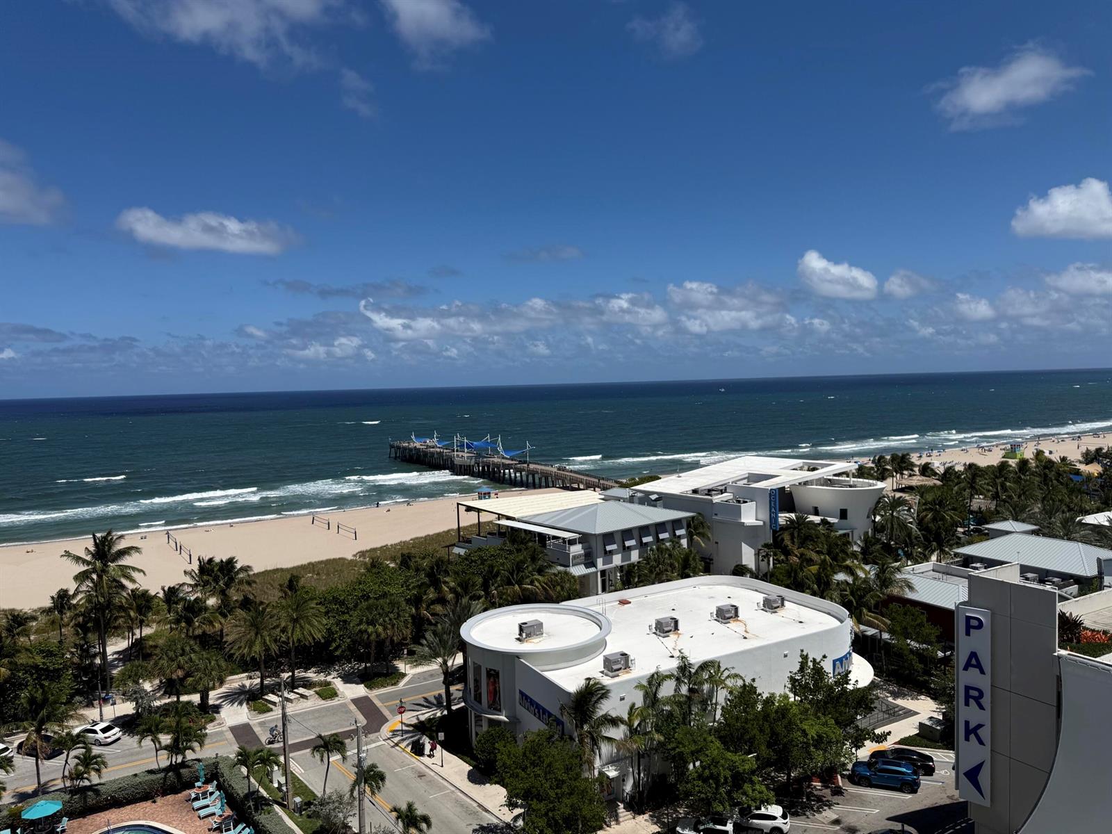 An elevated view shows a beach, a fishing pier, and surrounding buildings under a blue sky — 305 N Pompano Beach Boulevard # 1204, Pompano Beach FL 33062, POMPANO BEACH, FL