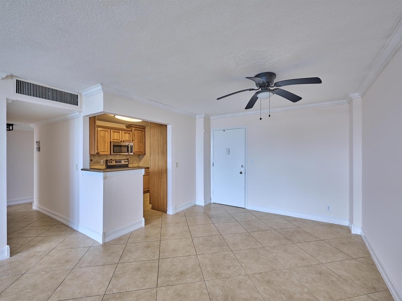 An open-concept living area features tile flooring, a ceiling fan, and an adjacent kitchen — 305 N Pompano Beach Boulevard # 1204, Pompano Beach FL 33062, POMPANO BEACH, FL