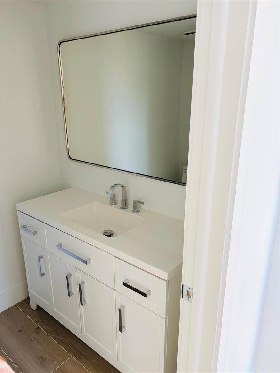 A white bathroom vanity with a chrome faucet and a rectangular mirror on the wall — 2404 Bridgewood Drive, Boca Raton FL 33434, BOCA RATON, FL