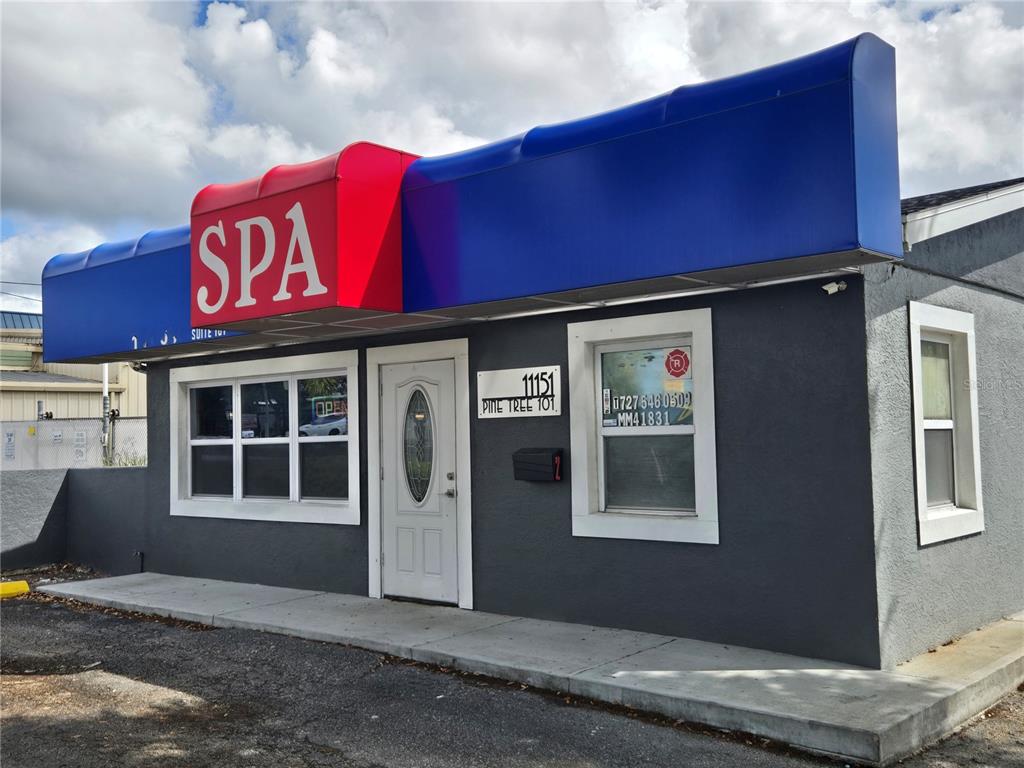 A single-story commercial building with a blue and red awning and a gray stucco exterior — 11151 66TH STREET, LARGO, FL