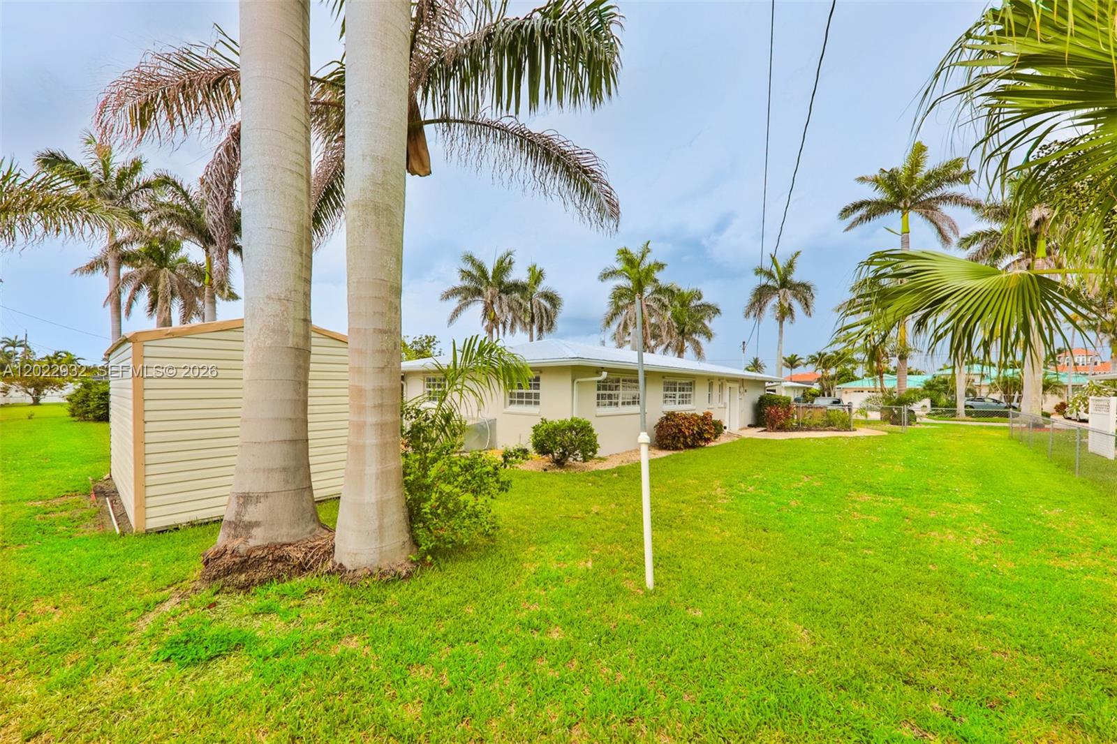 A light-colored house with a shed stands in a grassy yard with palm trees — 450 bayshore dr, Cape Coral FL 33904, CAPE CORAL, FL