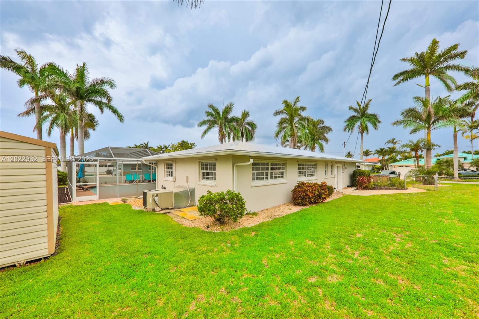 The exterior of a single-story house features a grassy yard, palm trees, and a pool — 450 bayshore dr, Cape Coral FL 33904, CAPE CORAL, FL