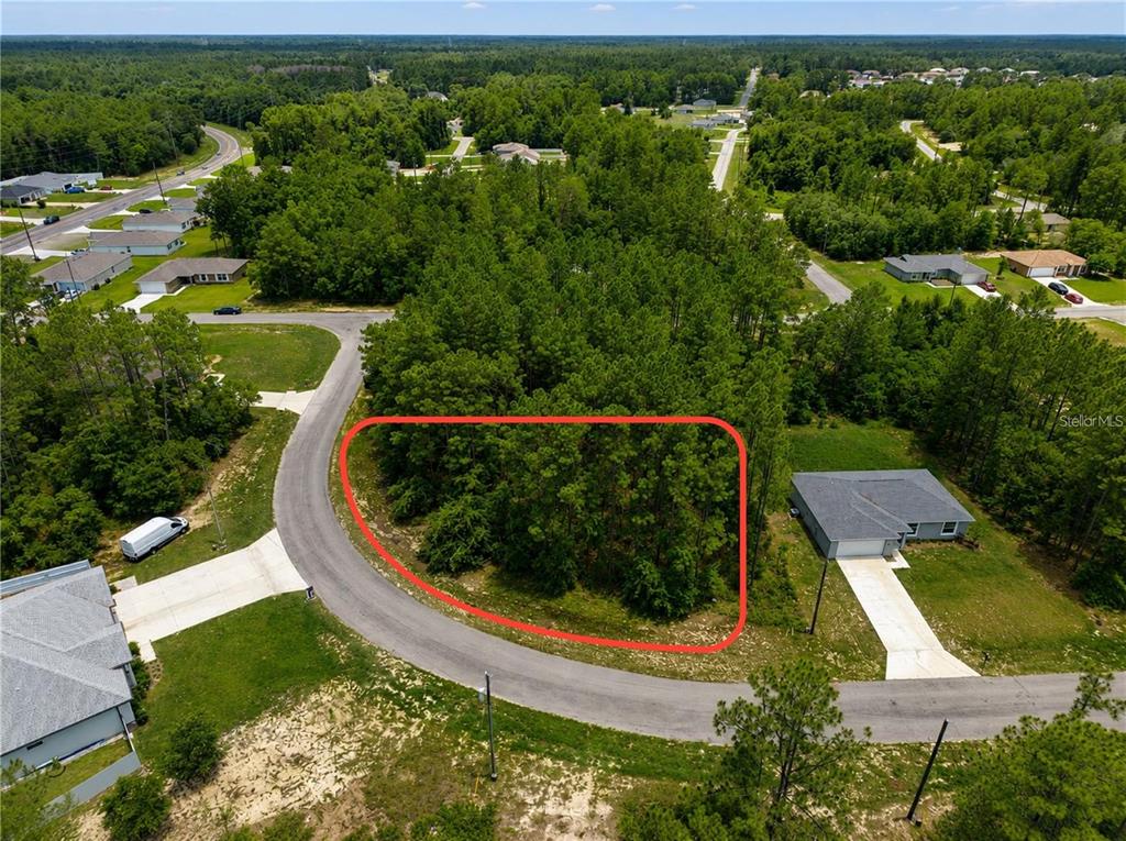 An aerial view shows a wooded, undeveloped residential lot outlined in red along a road — UNDETERMINED, OCALA, FL