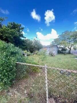 A chain-link fence borders a grassy backyard with trees and a small house in back — 6312 NW 17th Avenue, Miami FL 33147, MIAMI, FL