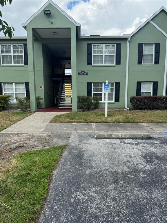 A two-story green apartment building features a central staircase and a designated handicap parking space — 2053 DIXIE BELLE DRIVE UNIT 2053P, ORLANDO, FL