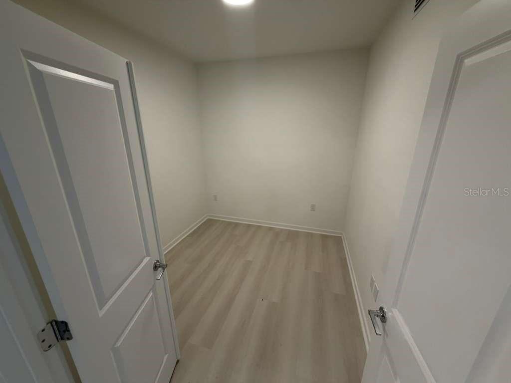 A small, empty room with light-colored wood-look flooring and white walls — 5587 MILLENIA PARK BOULEVARD UNIT 409, ORLANDO, FL
