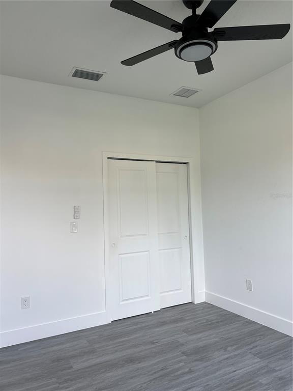 A bedroom features white walls, gray wood-look flooring, a ceiling fan, and a sliding closet — 200 FARLEY STREET SW, PALM BAY, FL