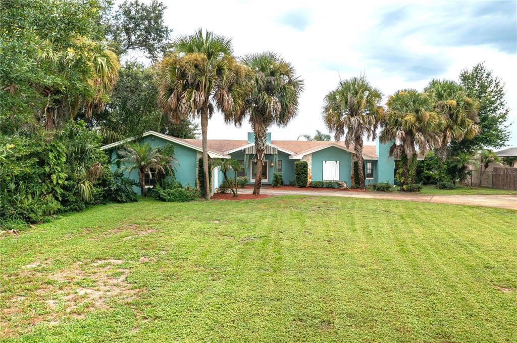 A single-story teal house with a large front lawn and several palm trees — 589 THORNBURG ROAD, BABSON PARK, FL