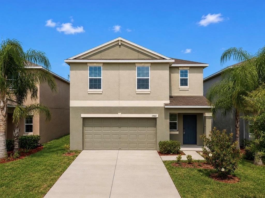 A two-story suburban house with a tan stucco exterior, a two-car garage, and palm trees — 17014 YELLOW PINE STREET, WIMAUMA, FL