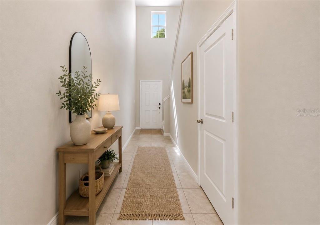 A bright entryway features a console table, a runner rug, and a tall arched window — 17014 YELLOW PINE STREET, WIMAUMA, FL