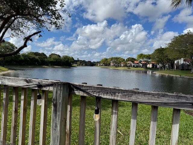 A wooden deck railing with string lights overlooks a lake surrounded by trees and houses — 5544 Fox Hollow Drive, Boca Raton FL 33486, BOCA RATON, FL
