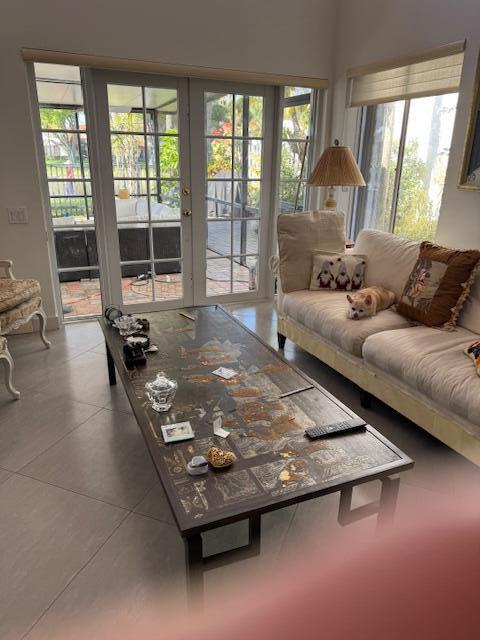 A bright living room with high ceilings, tile floors, a sofa, and large glass doors — 5544 Fox Hollow Drive, Boca Raton FL 33486, BOCA RATON, FL