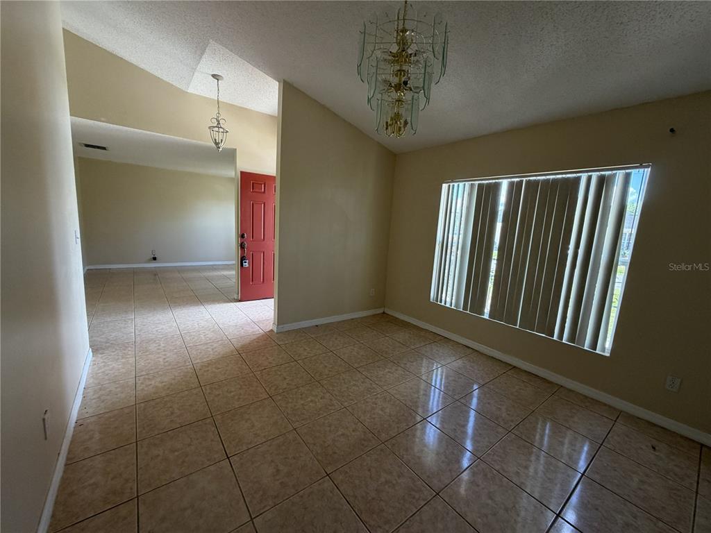A dining room with tile flooring, a chandelier, and a view of the front entrance — 1158 SAINT TROPEZ COURT, KISSIMMEE, FL