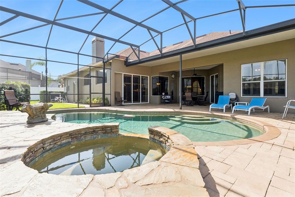 A screened-in patio features a swimming pool, a stone hot tub, and outdoor lounge chairs — 3739 WINDING LAKE CIRCLE, ORLANDO, FL