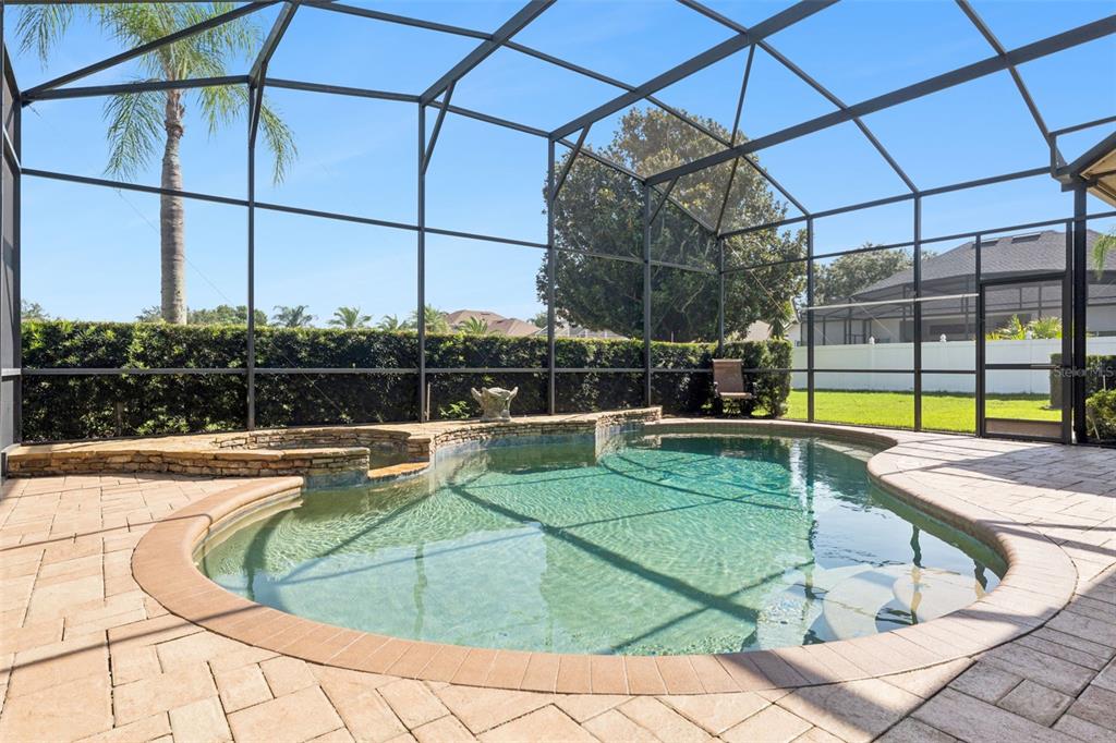 A screened-in pool area features a stone-accented spa and a paved patio deck — 3739 WINDING LAKE CIRCLE, ORLANDO, FL