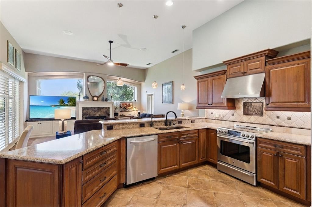 A kitchen with wood cabinets, granite countertops, and stainless steel appliances opens to a living area — 3739 WINDING LAKE CIRCLE, ORLANDO, FL