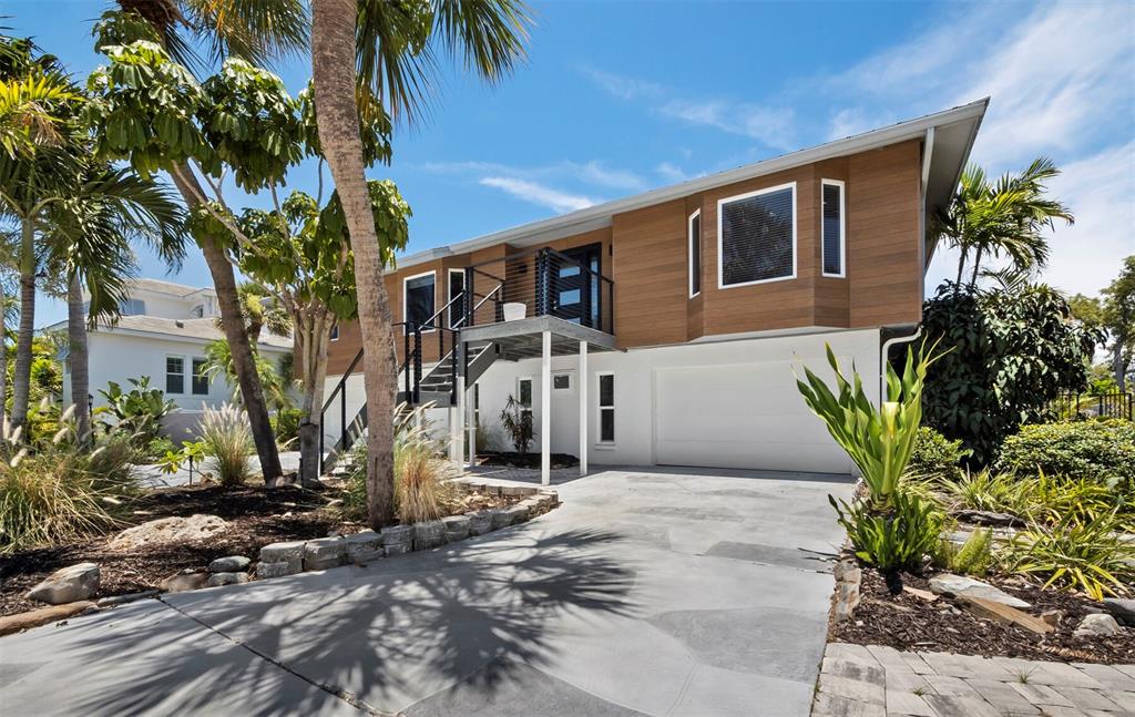 A two-story house with wood-paneled siding, an elevated deck, and a concrete driveway — 521 CUMMINGS STREET, SARASOTA, FL