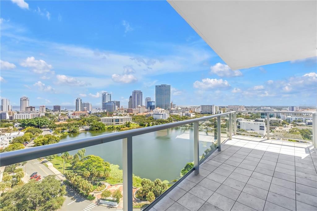 A high-rise balcony with tile flooring overlooks a lake and a city skyline — 777 3RD AVENUE N UNIT 1605, ST PETERSBURG, FL